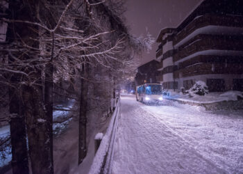 Electric taxi bus on snowy streets in the car-free Alpine mountain village at cold winter night